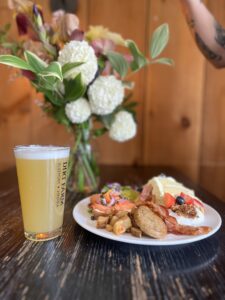 A plate of food loaded up at Dirt Farm Brewing's Mother's Day Brunch served with a beer and a bouquet of flowers