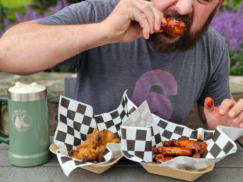 Man eating chicken wings at dirt farm brewings father's day king of the Wing event in Loudoun county virginia