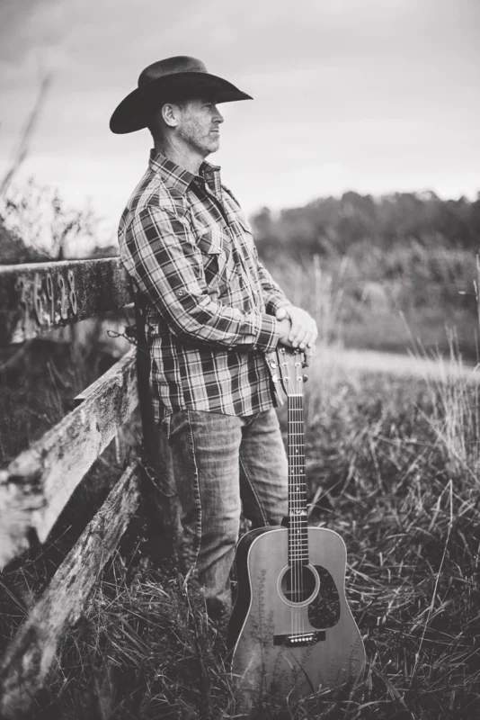 mark Cullinane, local musician, leaning up against a fence to play live music at Dirt Farm Brewing in Loudoun County virginia