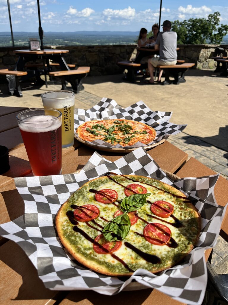 A table covered in beer and pizzas at Dirt farm Brewing during happy hour in Loudoun county virginia