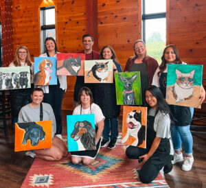 Guests showing off their artwork at the dirt farm brewing paint and sip paint your pet event