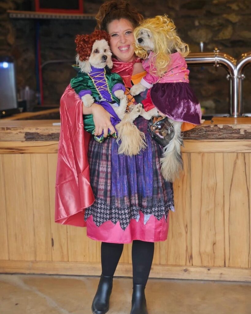 woman in a Sanderson sisters costume with her dogs at dirt farm brewings howl-o-ween event in Bluemont, virginia