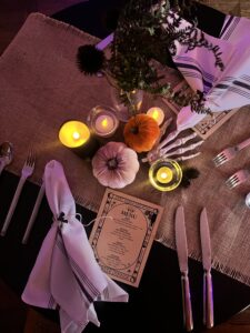 tablescape at dirt farm brewings Halloween Beer dinner with skeleton hands, pumpkins, candles and a menu in Loudoun county virginia