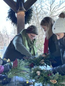 Jess of Walking Wind Farm and Florist helping a guest make a holiday wreath at dirt Farm brewings wild on your door workshop in Loudoun county, virginia