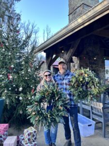 Guests showing off their wreaths from the wild on your door holiday wreath workshop at dirt farm Brewing in Loudoun county virginia