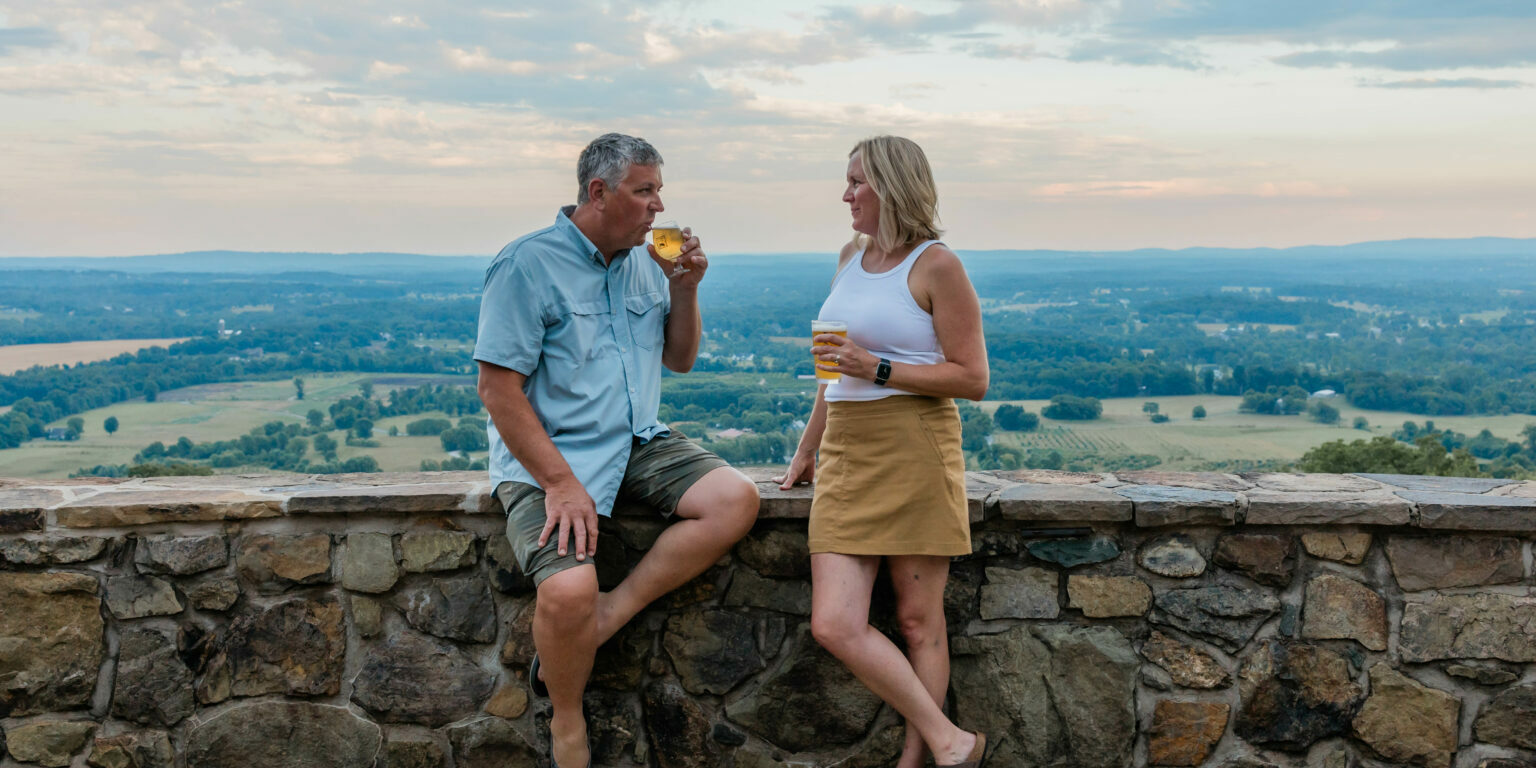 Owners of Dirt Farm Brewing Janell and Bruce Zurschmeide sharing a beer on the patio together. love loudoun